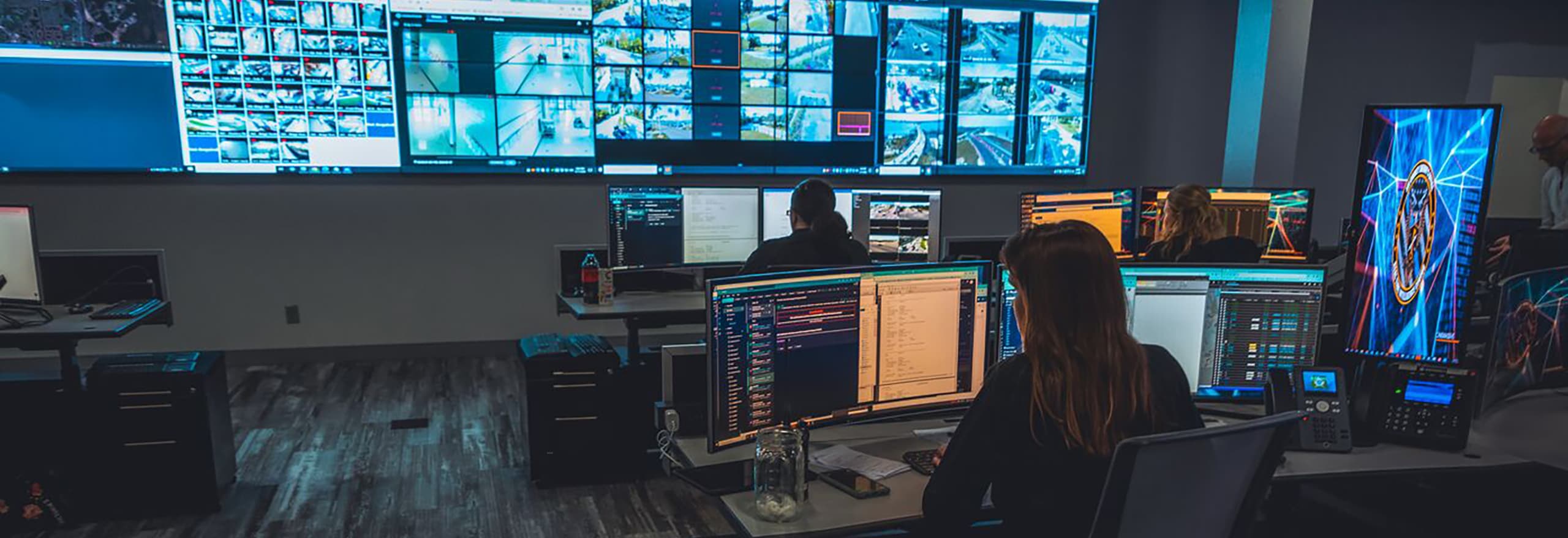 Medical dispatch coordination centre with large screens showing global flight tracking, operators wearing headsets at workstations