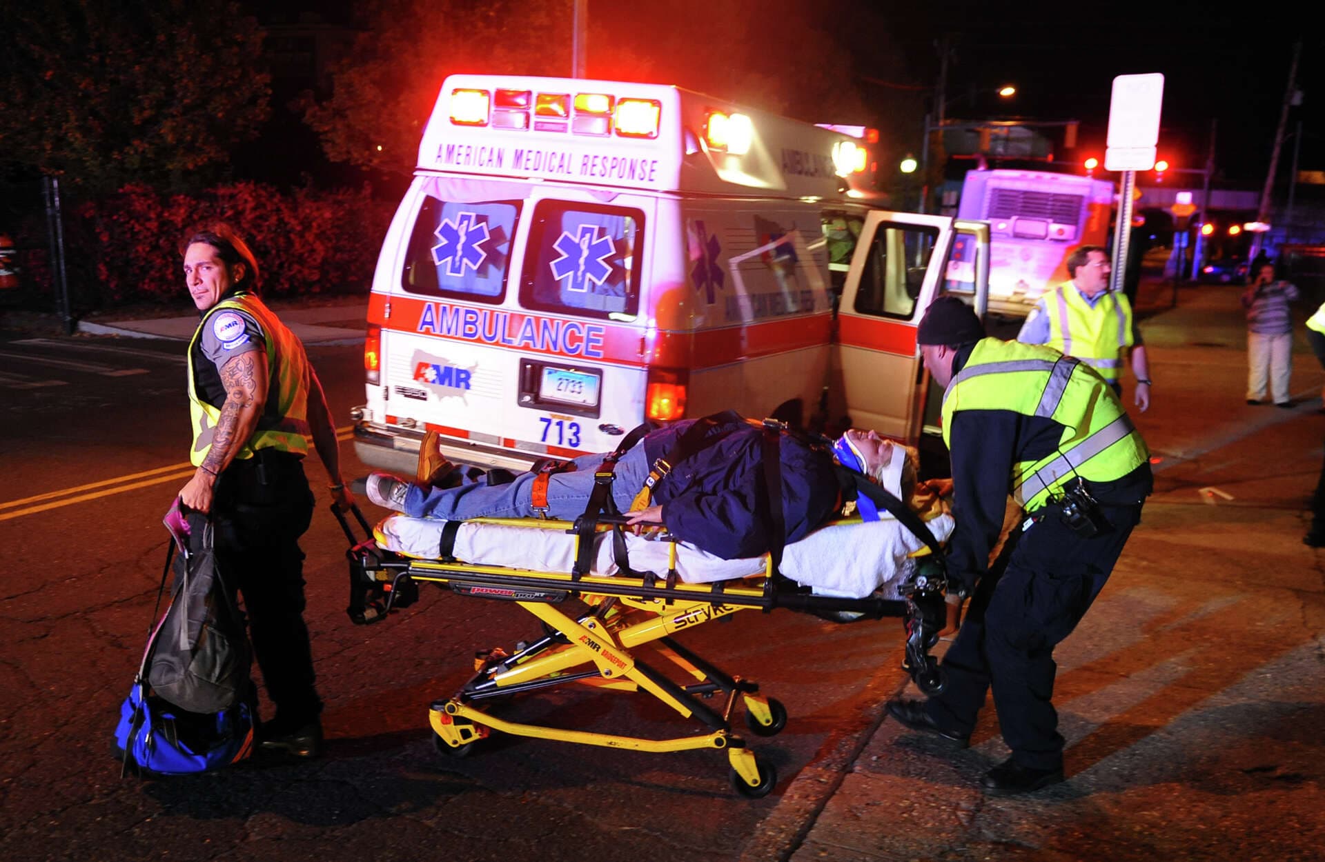Medical crew loading a patient on a stretcher onto an air ambulance aircraft on the tarmac at night
